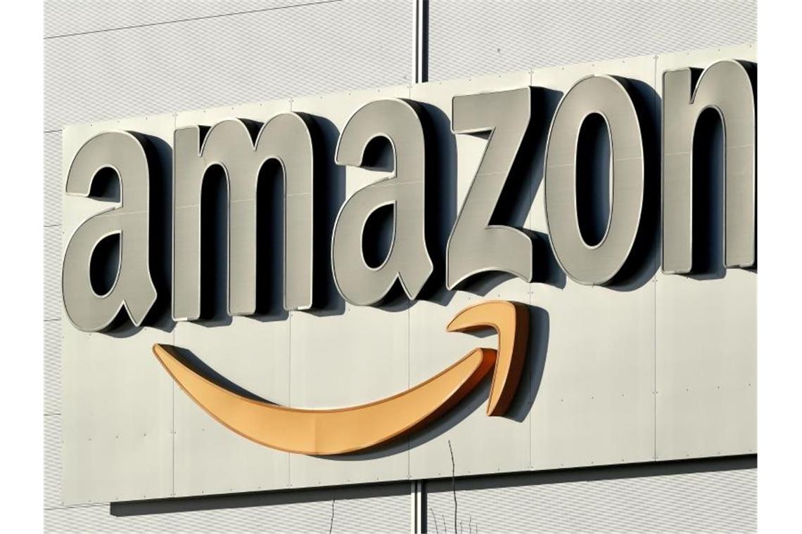 Logo und Schriftzug von Amazon an einem Paketzentrum des Online-Händlers. Foto: Holger Hollemann/dpa/Archiv