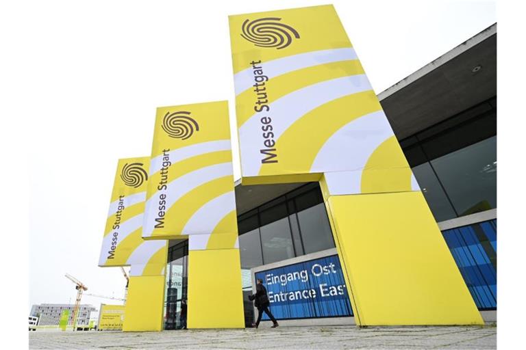 Logos der Messe Stuttgart stehen vor den Messehallen. Foto: Bernd Weißbrod/dpa