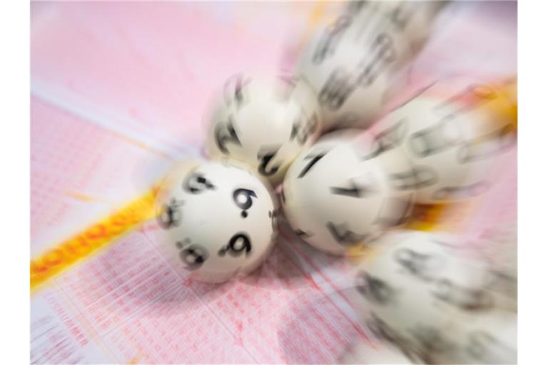 Lotto-Kugeln liegen auf einem Lottoschein. Foto: Tom Weller/dpa/Symbolbild
