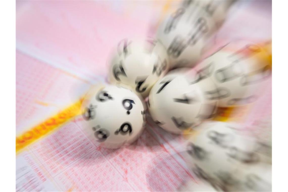 Lotto-Kugeln liegen auf einem Lottoschein. Foto: Tom Weller/dpa/Archivbild