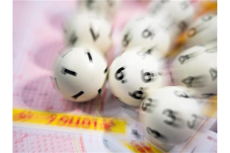 Lotto-Kugeln liegen auf einem Lottoschein. Foto: Tom Weller/dpa/Symbolbild