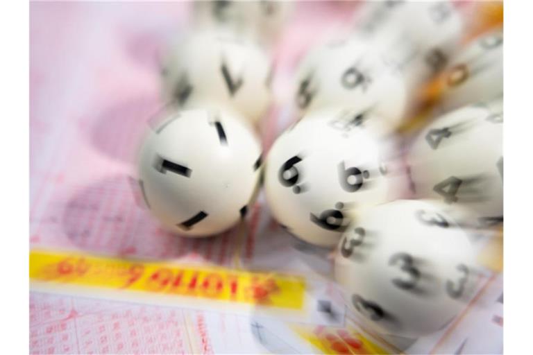 Lotto-Kugeln liegen auf einem Lottoschein. Foto: Tom Weller/dpa/Archivbild
