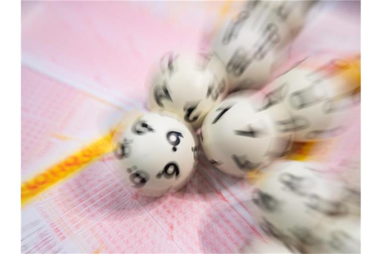 Lotto-Kugeln liegen auf einem Lottoschein. Foto: Tom Weller/dpa/Symbolbild