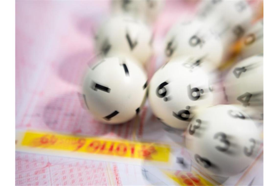 Lotto-Kugeln liegen auf einem Lottoschein. Foto: Tom Weller/dpa/Symbolbild