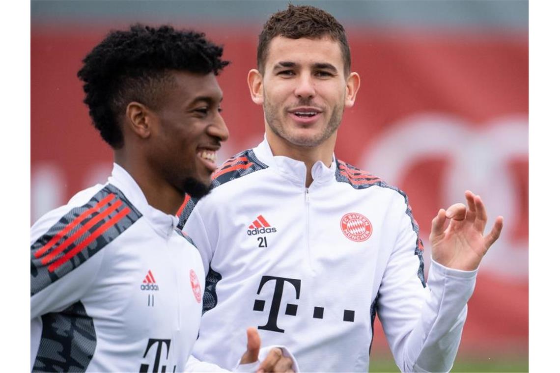 Lucas Hernández (r) joggte am Tag nach seinem Gerichtstermin bester Laune über den Trainingsrasen. Foto: Sven Hoppe/dpa