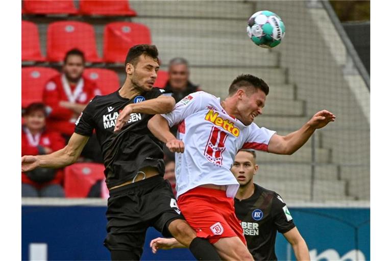 Lukas Fröde von Karlsruhe und Andreas Albers von Regensburg (l-r.) im Duell um den Ball. Foto: Armin Weigel/dpa