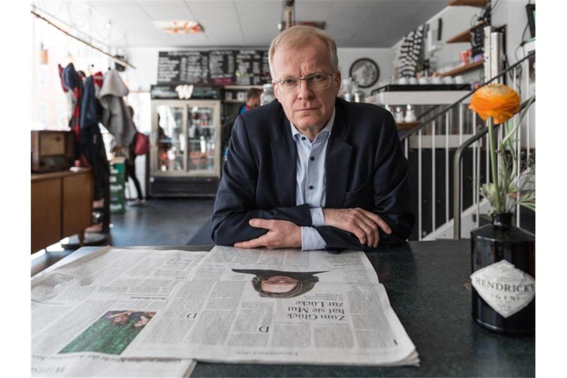 Lyriker Henning Ziebritzki sitzt an einem Schreibtisch und liest Zeitung. Foto: Björn Klein/Copyright: SWR/Björn Klein/dpa