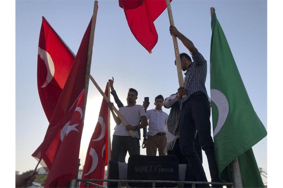 Männer schwenken in Akçakale Nationalflaggen und feiern die Erfolge der türkischen Truppen. Foto: Mehmet Guzel/AP/dpa