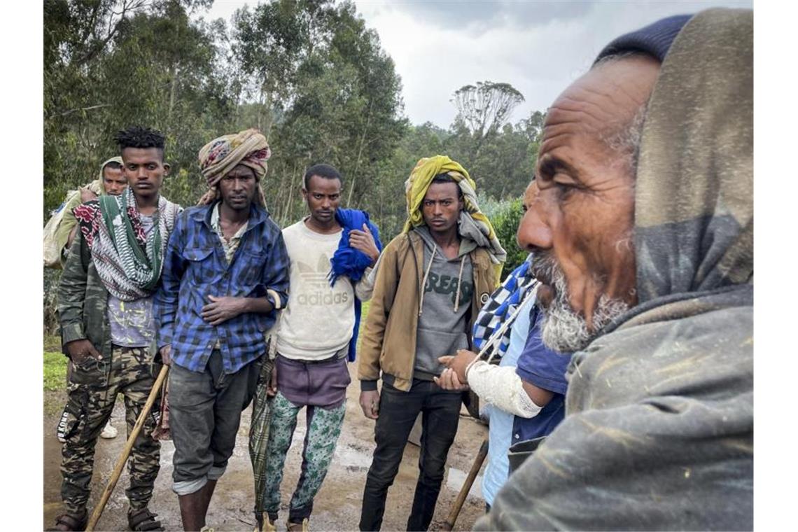 Männer versammeln sich, um mit dem am Arm verletzten Milizionär Kibret Bidere (2.v.r) in der Nähe des Dorfes in der Amhara-Region in Nordäthiopien zu sprechen. Foto: Uncredited/AP/dpa