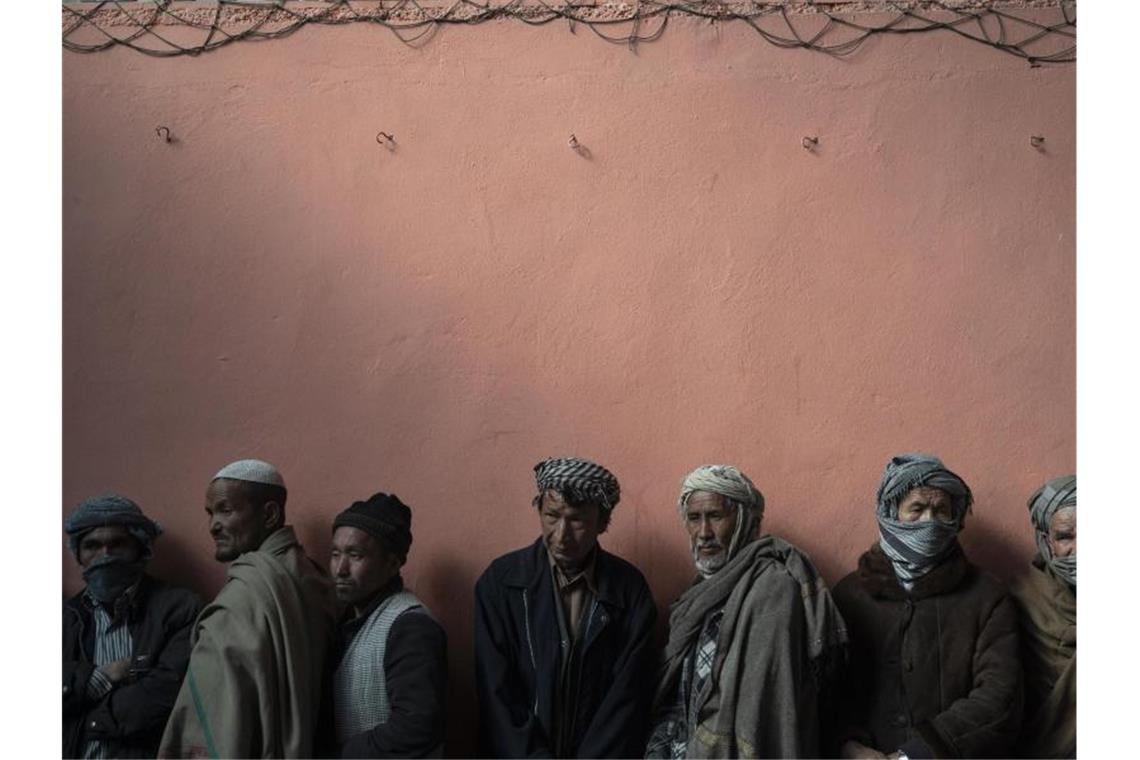 Tausende Afghanen fliehen täglich in den Iran Männer warten in einer Schlange, um bei einer vom Welternährungsprogramm (WFP) organisierten Geldverteilung Bargeld zu erhalten. Foto: Bram Janssen/AP/dpa