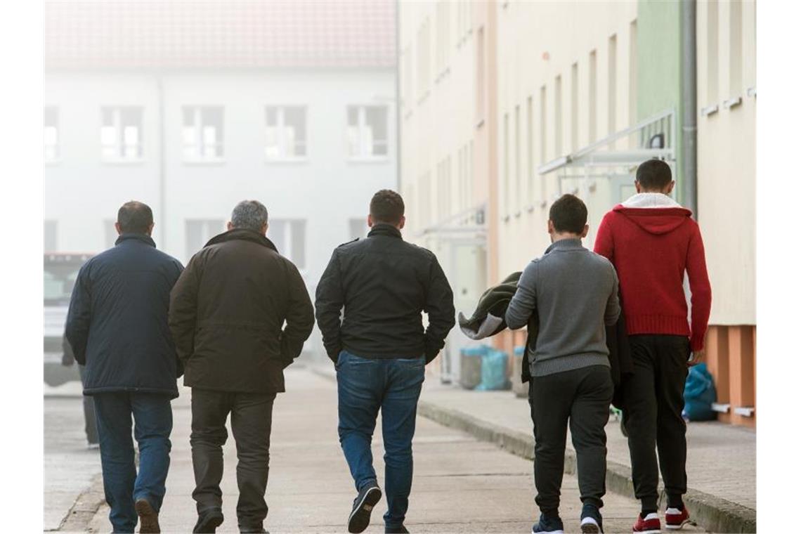 Männliche Asylbewerber gehen über das Gelände der Zentralen Ausländerbehörde (ZABH) in Eisenhüttenstadt. Foto: Patrick Pleul/dpa-Zentralbild/dpa