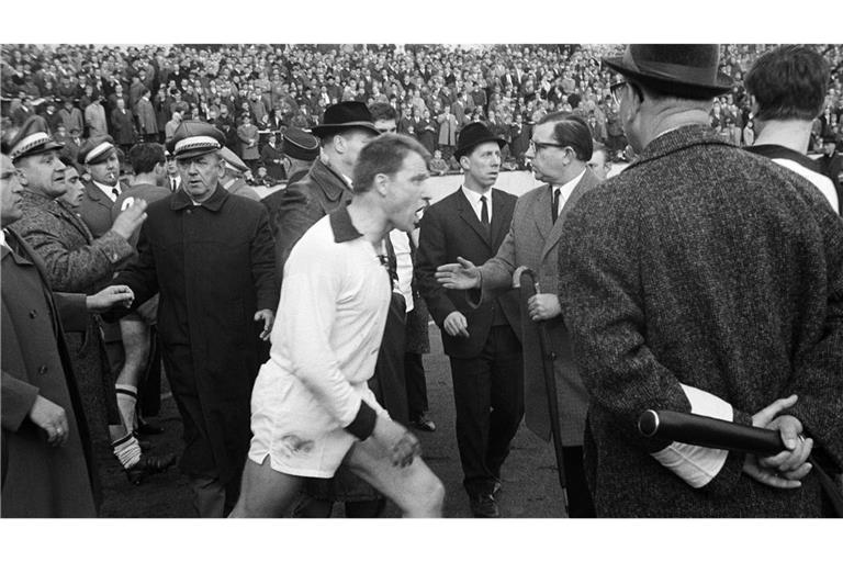 Man hört das Fluchen förmlich aus dem Bild  heraus: Karlheinz Mozin (SW Essen, Mi.)) wütend zwischen den Ordnern in den 1960ern bei einem Spiel der Regionalliga West.
