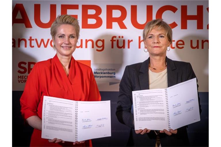 Manuela Schwesig (SPD, l), die Ministerpräsidentin von Mecklenburg-Vorpommern, und Simone Oldenburg (r), die Fraktionschefin der Linken im Landtag von Mecklenburg-Vorpommern, zeigen den unterzeichneten Koalitionsvertrag zwischen SPD und der Linken für eine gemeinsame Regierungsbildung in Mecklenburg-Vorpommern. Foto: Jens Büttner/dpa-Zentralbild/dpa