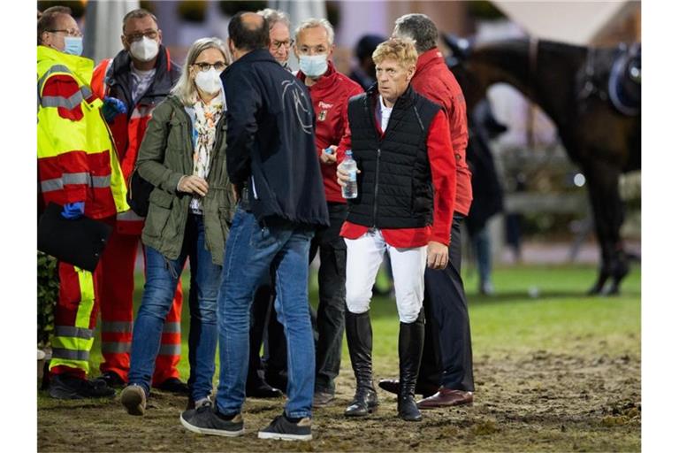 Marcus Ehning (2.v.r) steht nach seinem Sturz neben Sanitätern und Ärzten und Bundestrainer Otto Becker (r). Foto: Rolf Vennenbernd/dpa