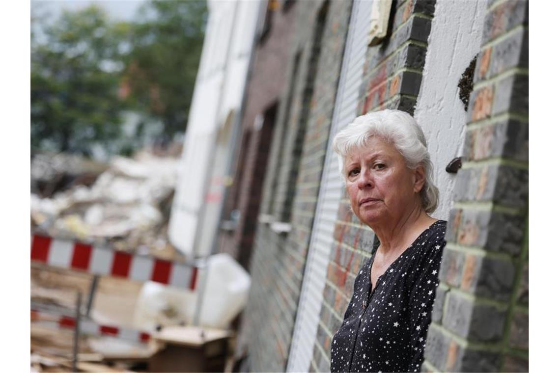 Maria Dunkel, Anwohnerin in Erftstadt-Blessem, blickt aus dem Eingang ihrer Wohnung. In Erftstadt tat sich in der Nacht zum 15. Juli die Erde auf und verschlang mehrere Häuser. Foto: Oliver Berg/dpa