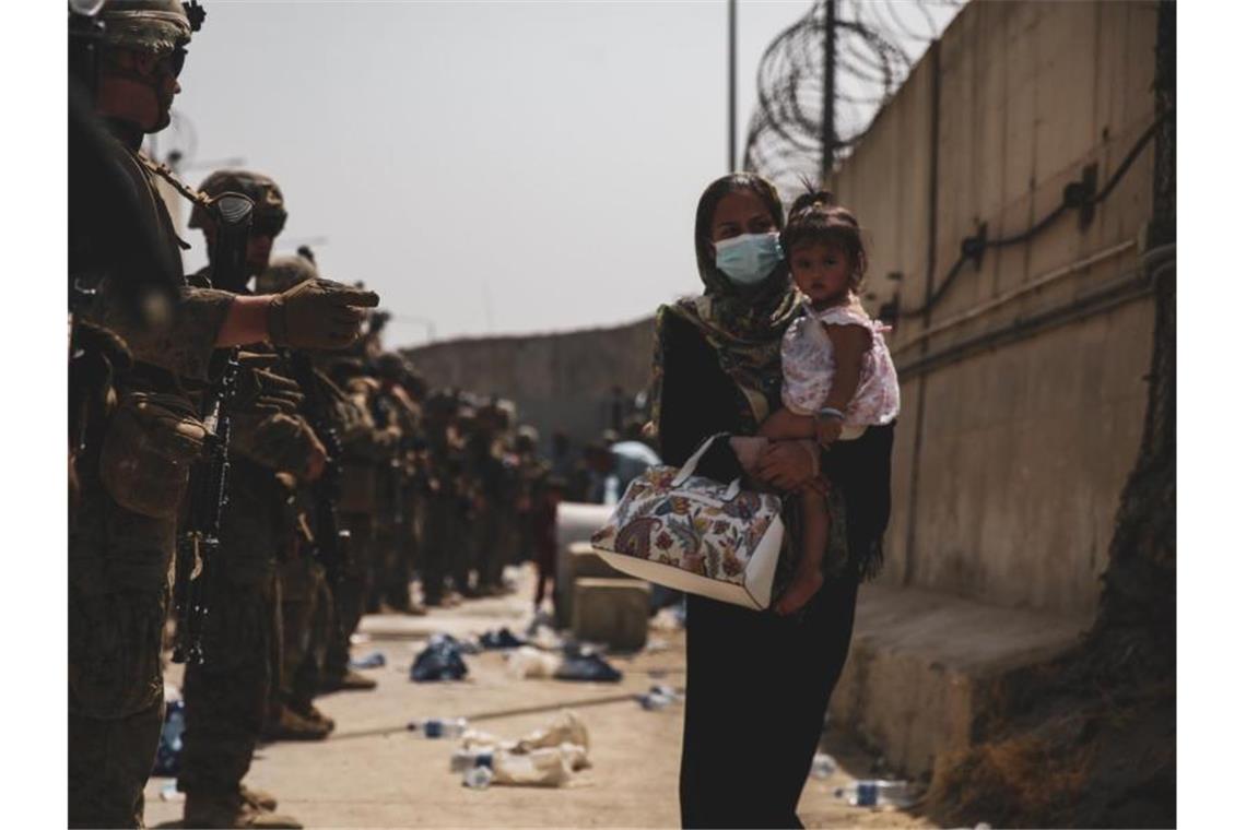 Marinesoldaten führen eine Frau, die ein Kind auf dem Arm trägt, während einer Evakuierung am Flughafen in Kabul. Foto: U.S. Marines/ZUMA Press Wire Service/dpa