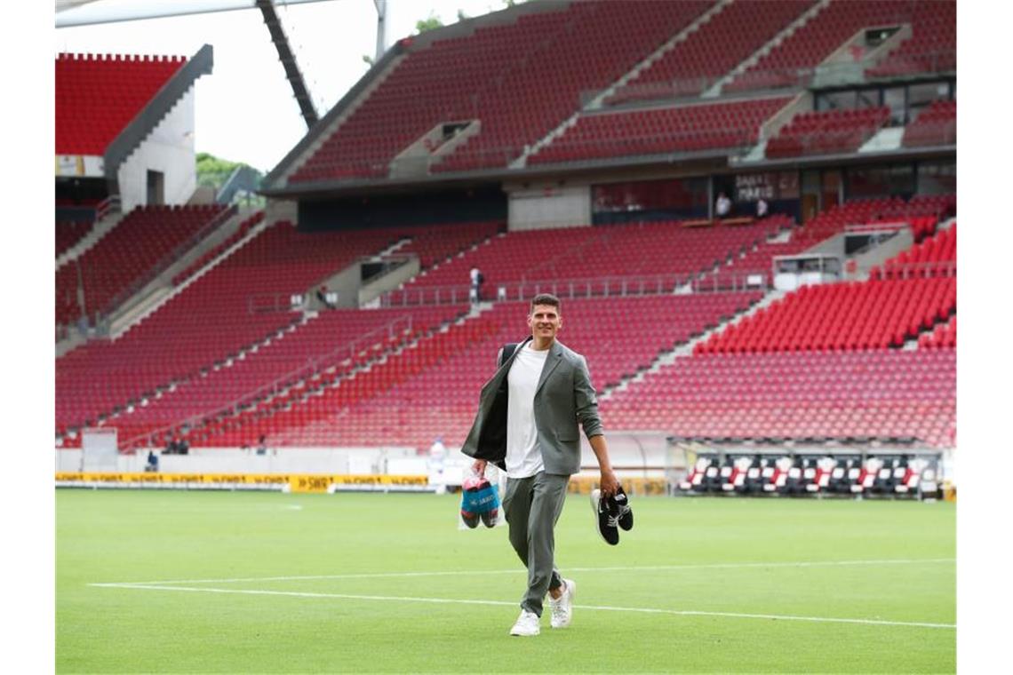 Mario Gomez hat seine Fußballschuhe ausgezogen und verlässt das Spielfeld. Foto: Tom Weller/dpa
