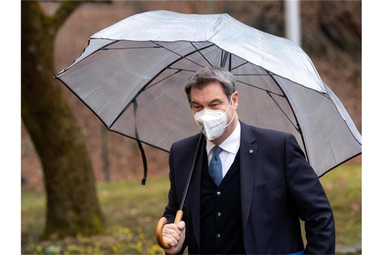 Markus Söder (CSU), Ministerpräsident von Bayern, kommt unter einem Regenschirm zur Pressekonferenz nach der Kabinettssitzung. Foto: Sven Hoppe/dpa
