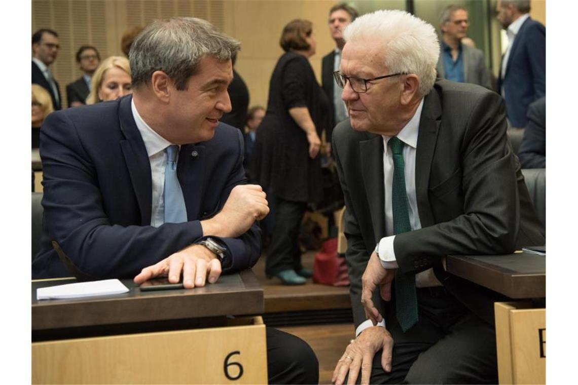 Markus Söder (l, CSU) und Winfried Kretschmann (Bündnis 90/Die Grünen) unterhalten sich im Bundesrat. Foto: Jörg Carstensen/dpa/Archivbild