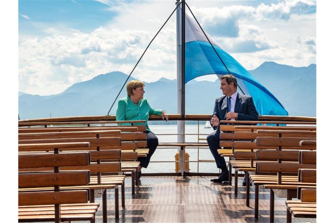 Markus Söder und Bundeskanzlerin Merkel fahren mit einem Schiff der Chiemsee-Schifffahrt auf die Insel Herrenchiemsee. Foto: Peter Kneffel/dpa/Pool/dpa