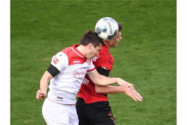 Markus Suttner von Düsseldorf und Janik Haberer von Freiburg (l-r.) im Zweikampf um den Ball. Foto: Patrick Seeger/dpa