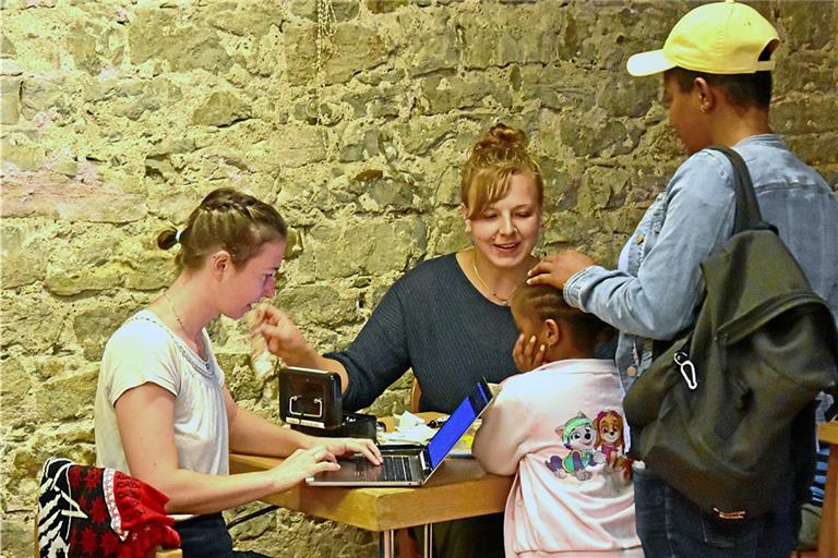 Marleen Krysl (links) und Ulrike Oesterle (Mitte) sind ehrenamtlich für die Awo tätig. Sie nehmen die Gutscheine der Geflüchteten entgegen und zahlen ihnen deren Gegenwert in bar aus.  Foto: Tobias Sellmaier