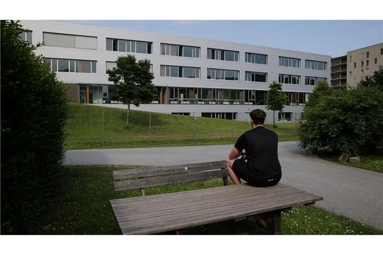 Marvin sitzt auf einem Tisch vor einem Schulgebäude und betet für die Opfer des Amoklaufs an einem Gymnasium. Ein 21-Jähriger hatte neun Menschen getötet und danach Suizid begangen.