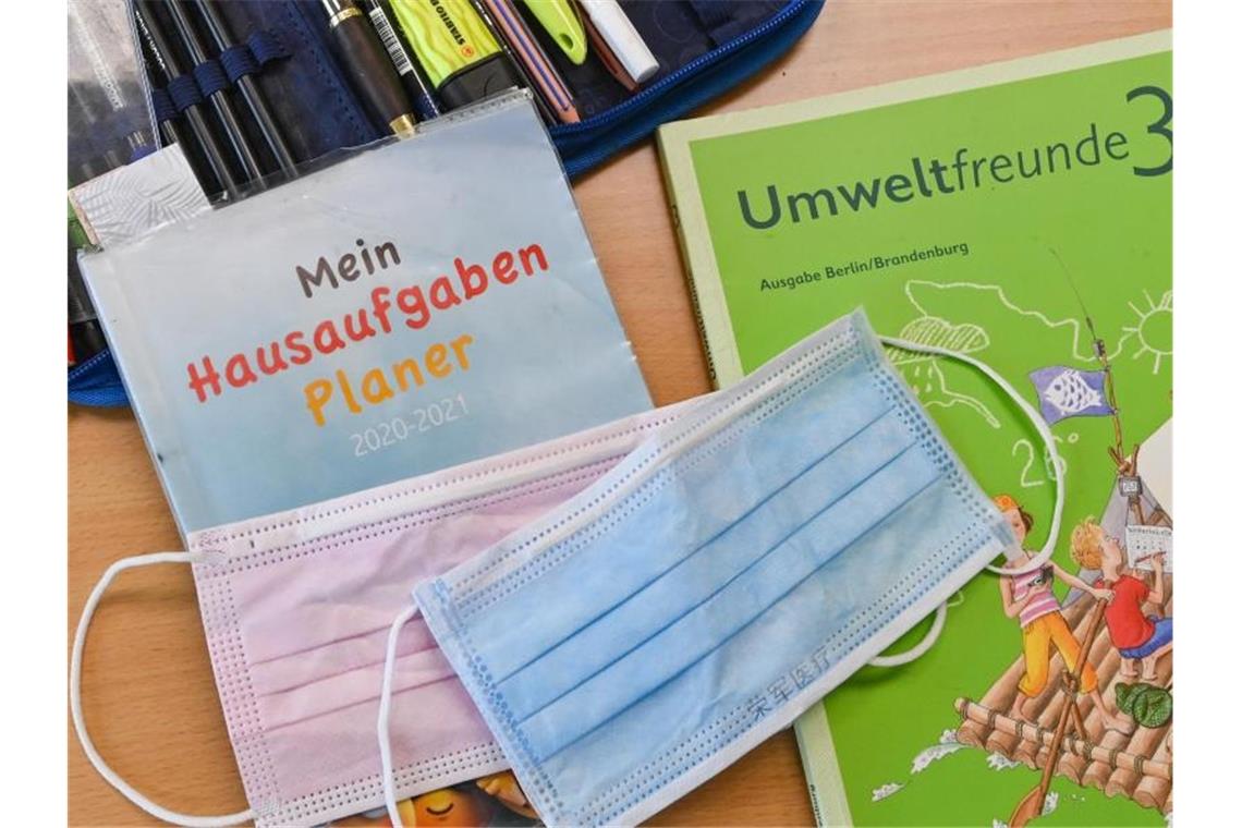 Masken liegen auf Arbeitsmaterialien eines Schülers. Foto: Patrick Pleul/dpa-Zentralbild/ZB/Symbolbild