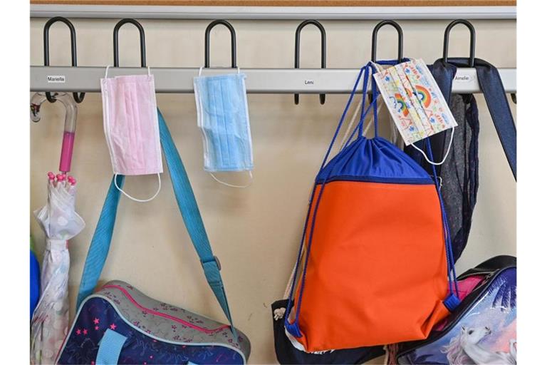 Masken und Taschen hängen in einer Grundschule an Kleiderhaken. Foto: Patrick Pleul/dpa-Zentralbild/dpa/Symbolbild