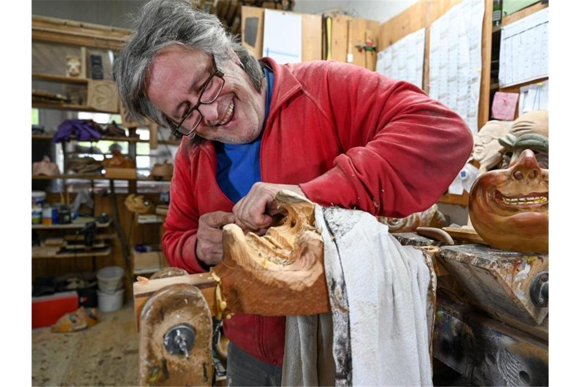 Maskenschnitzer Jogi Weiß schnitzt in seiner Werkstatt eine Maske aus Holz. Foto: Felix Kästle/dpa/Archivbild