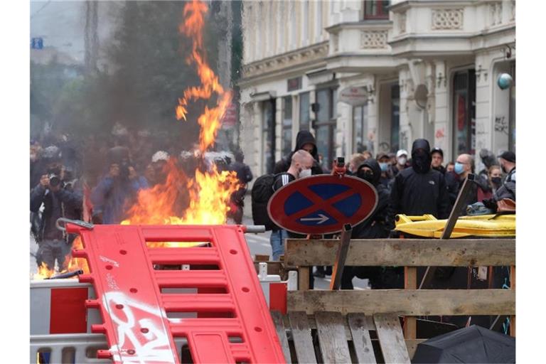 Maskierte Demo-Teilnehmer stehen hinter einer Barrikade. Foto: Sebastian Willnow/dpa-Zentralbild/dpa