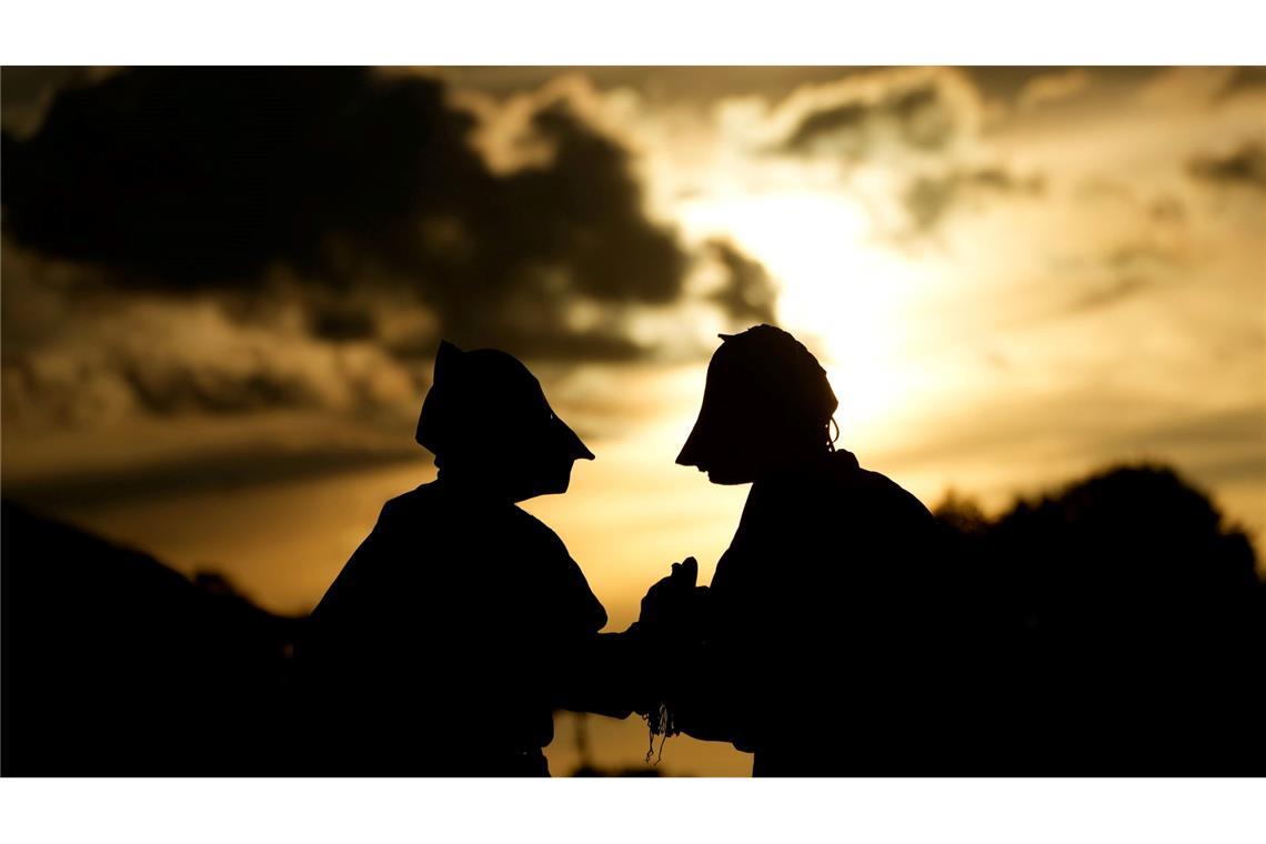 Maskierte Freischärler schauen sich bei Sonnenuntergang eine traditionelle Reitershow an.