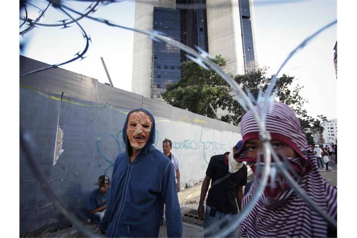 Venezuelas Präsident Maduro stellt den USA ein Ultimatum Maskierte Menschen protestieren gegen den venezolanischen Präsidenten Maduro. Foto: Boris Vergara