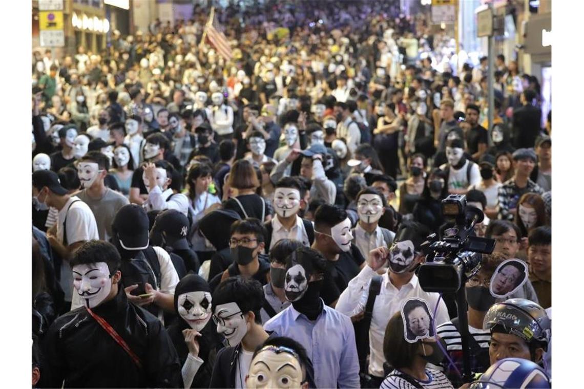 Chinas Führung zieht Zügel in Hongkong enger Maskierte Demonstranten versammeln sich auf einer Straße in Hongkong. Foto: Kin Cheung/AP/dpa