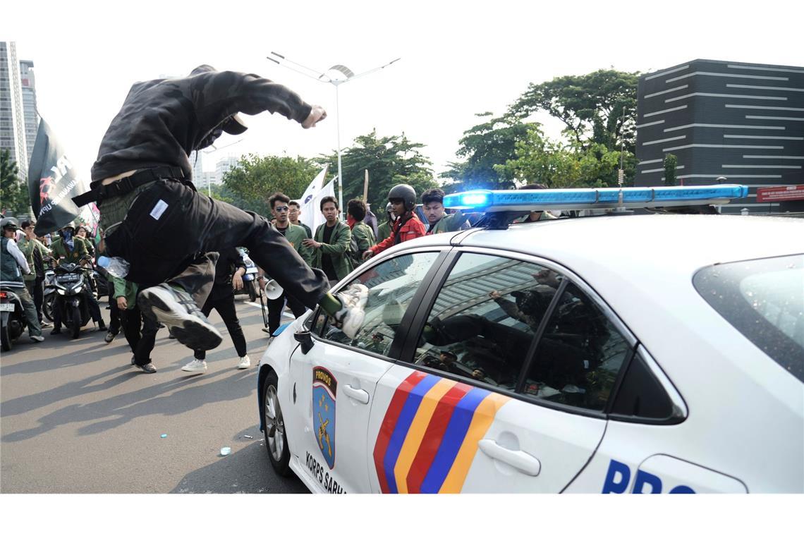 Bilder des Tages Massenproteste gegen die Regierung in Indonesien: ein Demonstrant attackiert ein Polizeiauto.