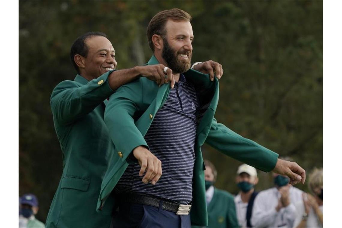 Masters-Champion Johnson wird im grünen Jackett emotional Masters-Champion Dustin Johnson (r) bekam von Vorjahressieger Tiger Woods das grüne Jackett angezogen. Foto: Charlie Riedel/AP/dpa