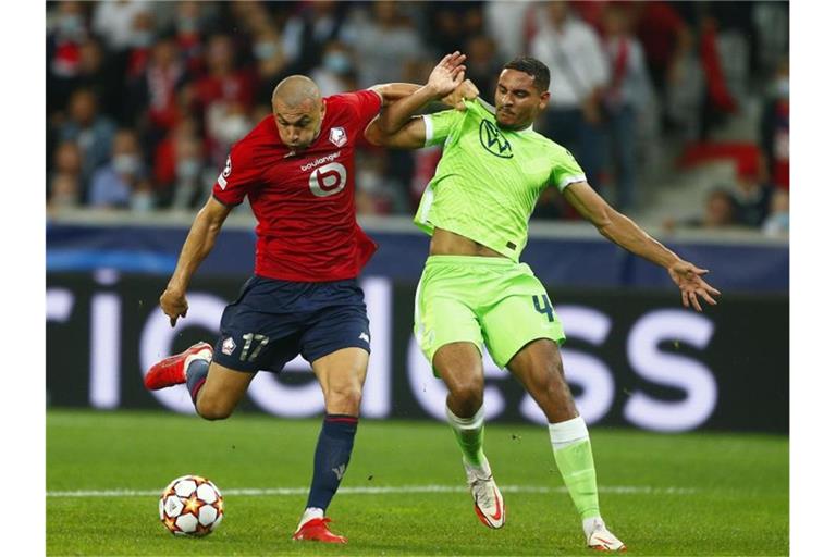 Maxence Lacroix vom VfL Wolfsburg (r) kann sich im Kampf um den Ball nicht gegen Burak Yilmaz vom OSC Lille durchsetzen. Foto: Michel Spingler/AP/dpa