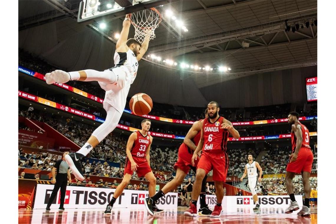 Maximilian Kleber (l) hängt nach einem Dunking am Korb. Foto: Swen Pförtner