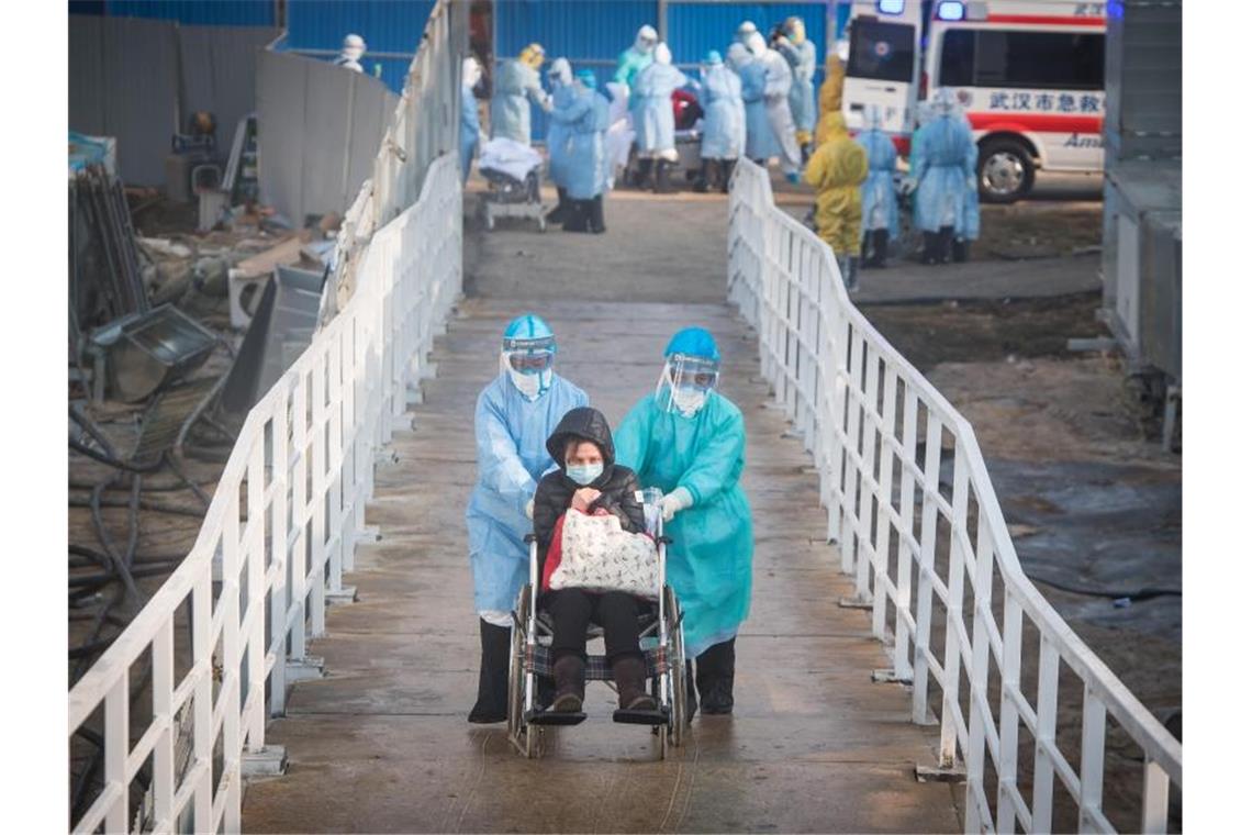 Mediziner helfen Corona-Patienten in Wuhan beim Umzug in die Isolierstationen eines neuen Behelfskrankenhauses mit rund tausend Betten. Foto: Xiao Yijiu/XinHua/dpa