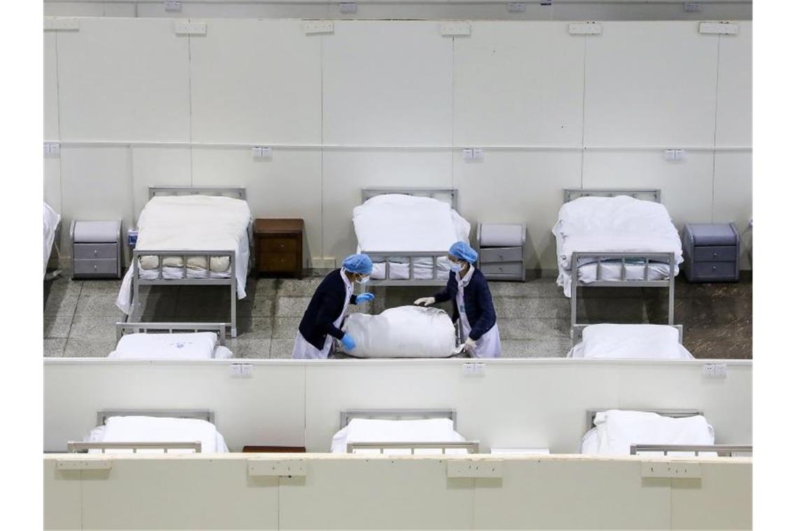 Medizinisches Personal bereitet Betten in einem provisorischen Krankenhaus vor. Foto: Uncredited/CHINATOPIX/AP/dpa