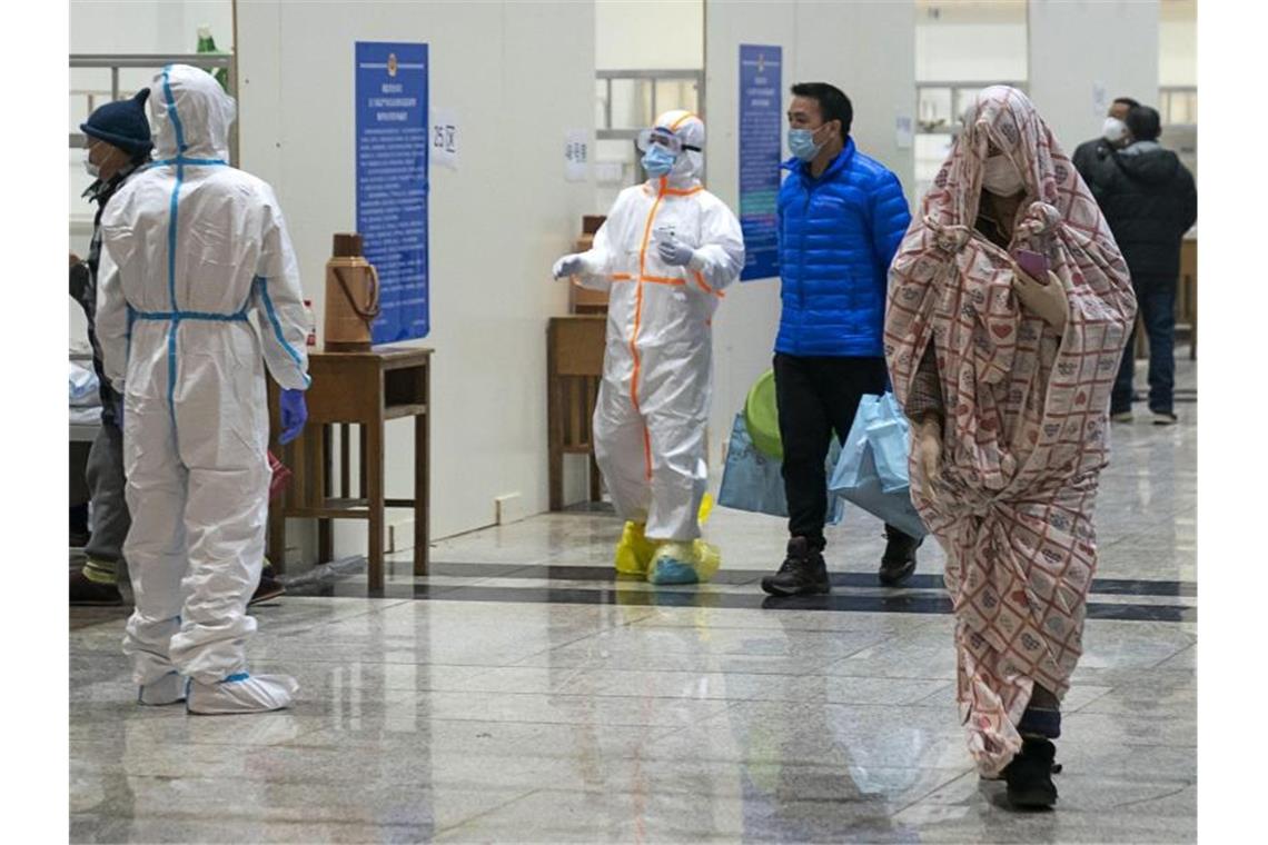 Medizinisches Personal kümmert sich in einem provisorischen Krankenhaus um Patienten, die sich mit dem Coronavirus infiziert haben. Foto: Uncredited/CHINATOPIX/AP/dpa
