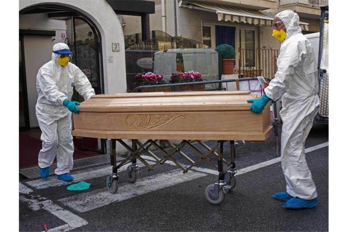 Medizinisches Personal trägt einen Sarg mit dem Leichnam einer 87-jährigen Frau aus einem Hotel im italienischen Laigueglia. Foto: AP/dpa