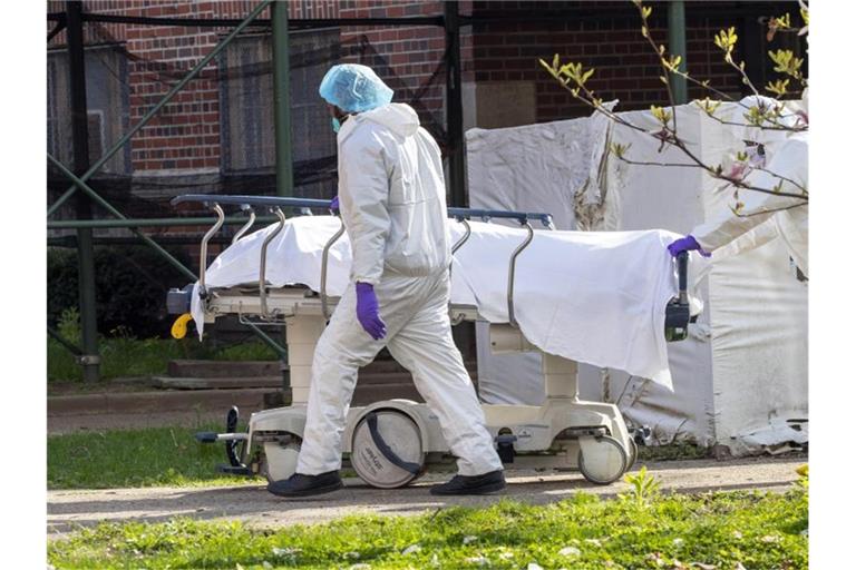 Medizinisches Personal transportiert eine Leiche aus einem Kühlwagen. Foto: Mary Altaffer/AP/dpa/Archiv