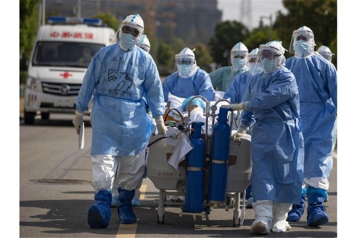 Medizinisches Personal in Schutzanzügen schiebt in Wuhan einen Covid-19-Patienten über eine Straße, um ihn in die Intensivstation zu verlegen. Foto: Shen Bohan/Xinhua/dpa