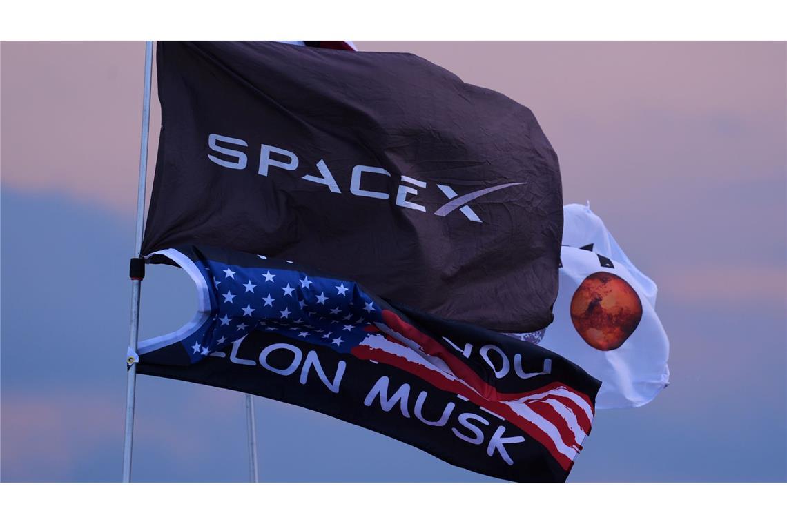 Zehnter Testflug von Rakete Starship um einen Tag verschoben Mehrere Fahnen, darunter zwei mit dem Aufdruck SpaceX und Elon Musk, sind in der Nähe des Startortes.