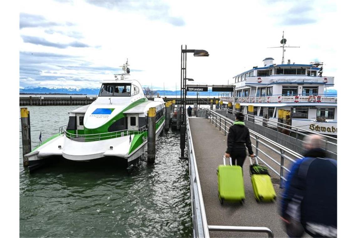Katamarane wegen Lockdowns ab Samstag stark eingeschränkt Mehrere Fußgänger laufen auf der Mole zum Katamaran, der auf dem Bodensee nach Konstanz fährt. Foto: Felix Kästle/dpa/Archivbild