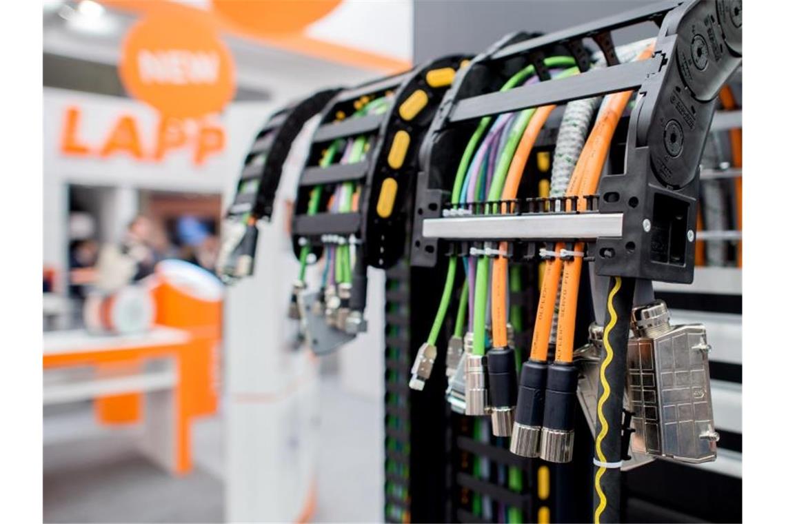 Mehrere Kabel hängen am Stand des Unternehmens Lapp bei einer Messe. Foto: Hauke-Christian Dittrich/dpa/Archivbild