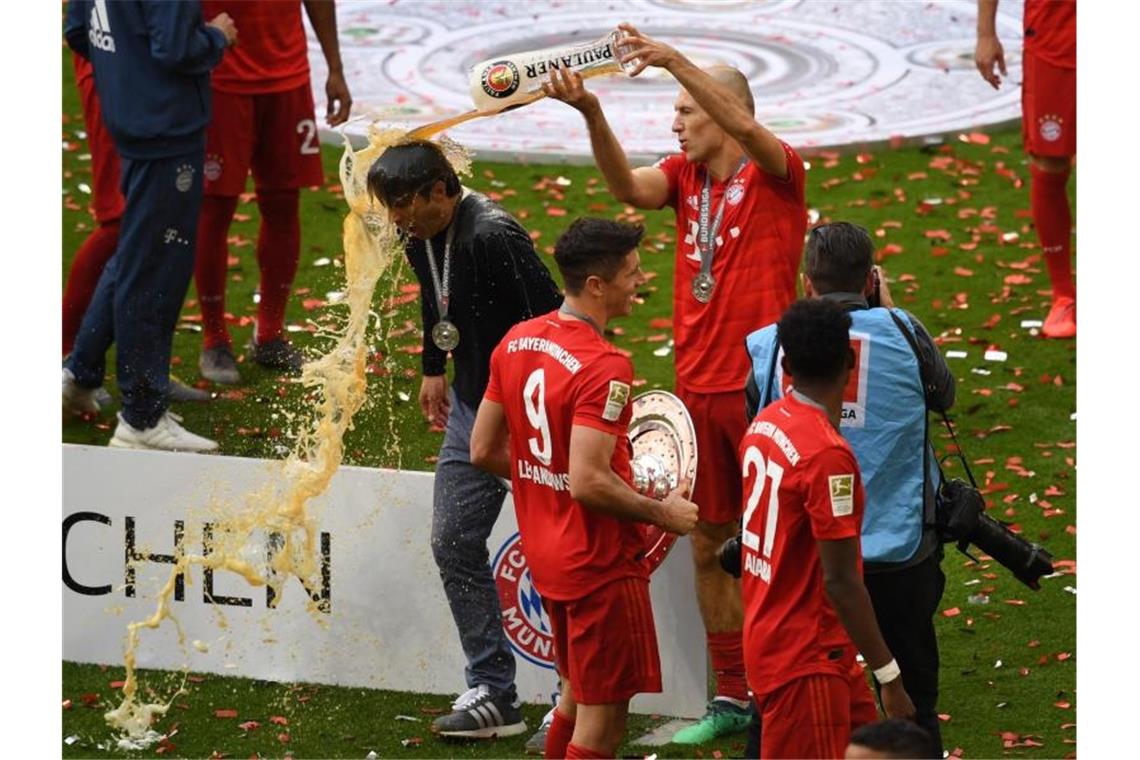 FC Bayern zum 29. Mal Meister - Dortmund-Sieg wertlos Meister-Coach Niko Kovac (l) bekommt eine Bierdusche von Arjen Robben. Foto: Sven Hoppe