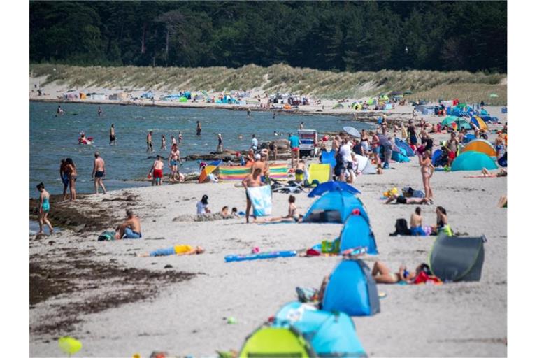 Menschen am Strand von Lubmin. Viele Ostseebäder machen derzeit mit Aushängen auf die Gefahr durch Vibrionen aufmerksam. Foto: Stefan Sauer/dpa