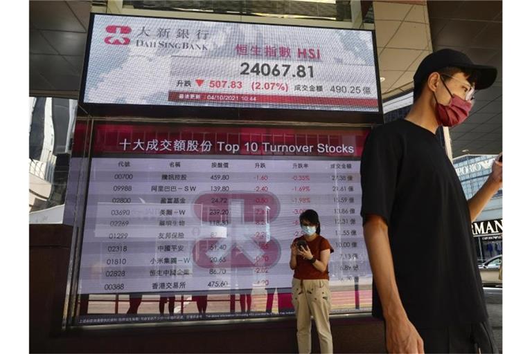 Menschen an der elektronischen Tafel einer Bank, die den Aktienindex an der Hongkonger Börse anzeigt. Foto: Vincent Yu/AP/dpa